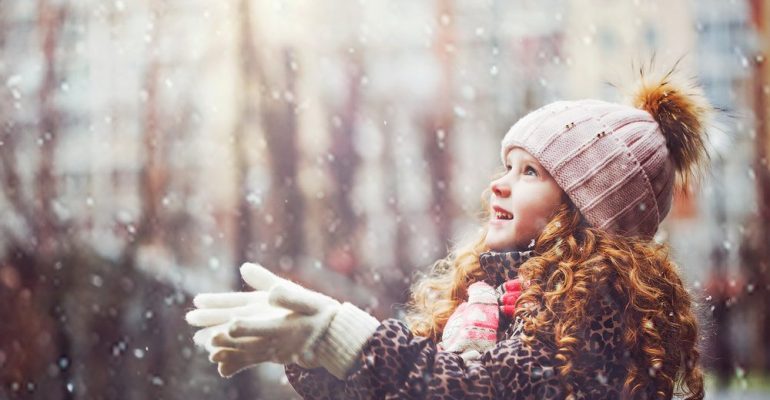 Cute-little-girl-stretches-her-hand-to-catch-falling-snowflakes.-First-snow.-Toning-instagram-filter.-Yuliya-Evstratenkos